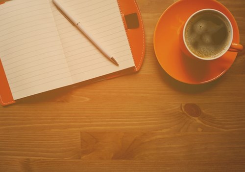 Kopp kaffe och anteckningsbok på skrivbord